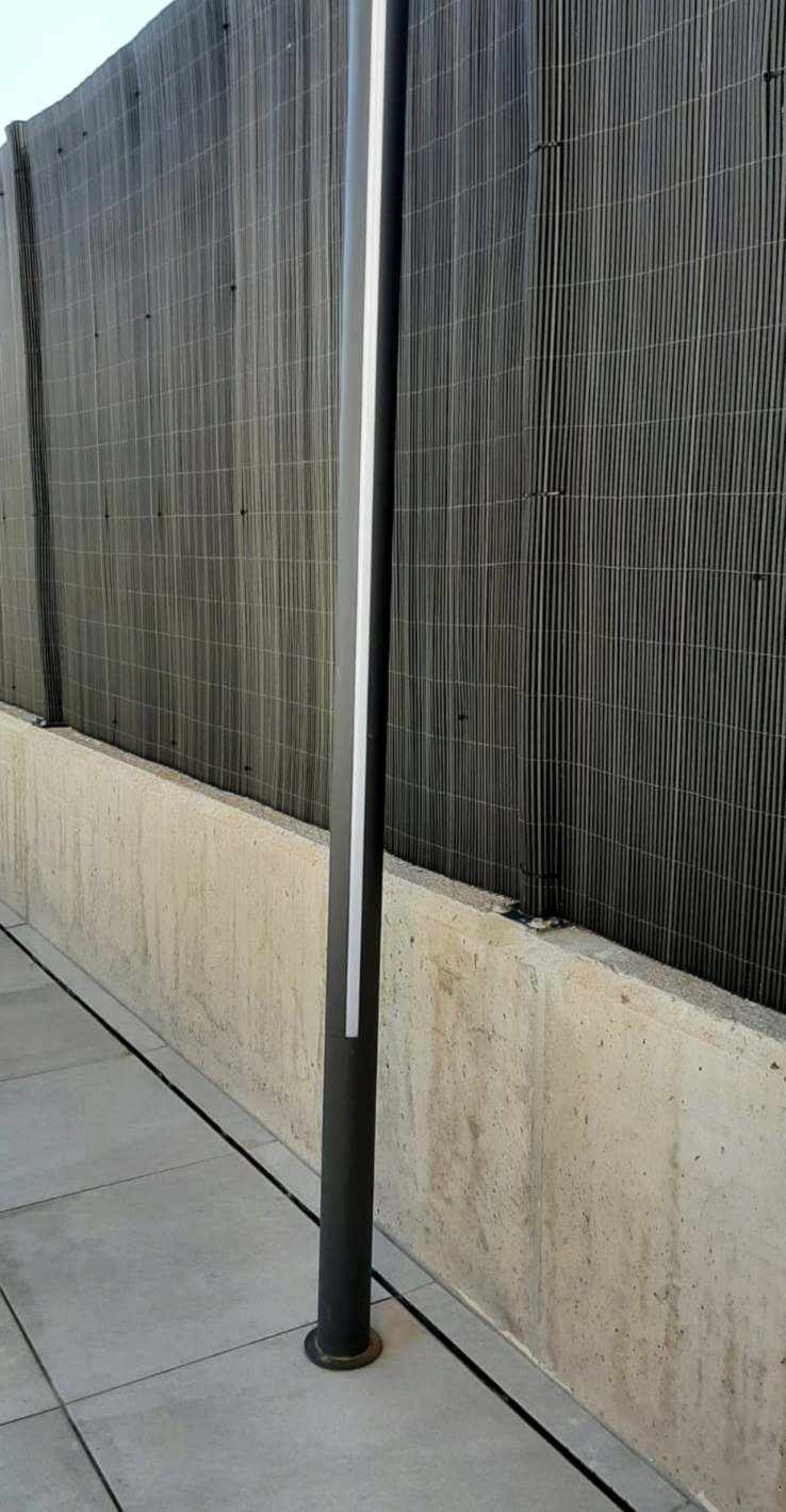 Columna de exterior con una franja de LED vertical, instalada en el suelo de una terraza