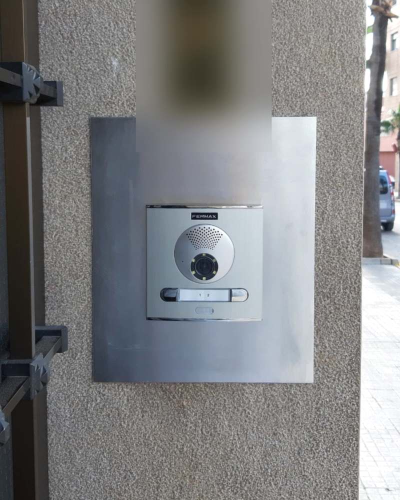 La misma entrada con una placa de videoportero nueva de acero inoxidable con cámara